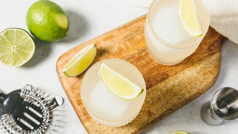 Daiquiris on a board with lime and tools