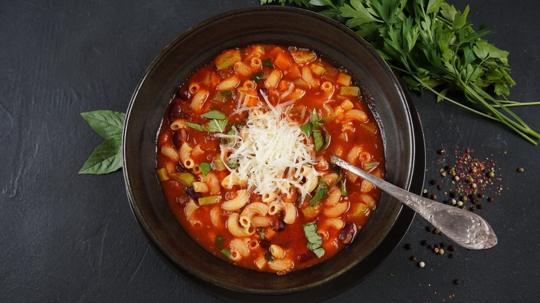 Pasta and beans in black bowl on black surface.