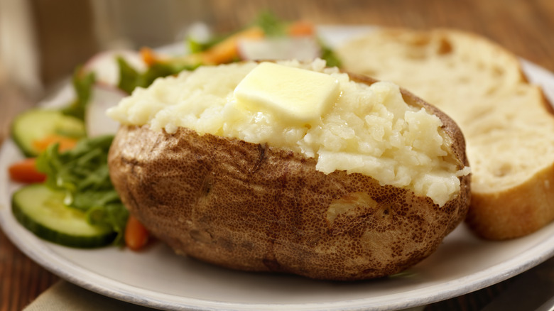 Baked potato with butter on white plate