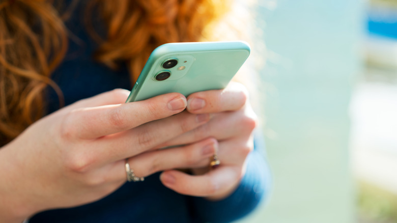 Closeup hands holding cell phone in light blue case