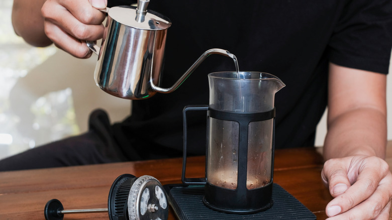 Water poured into a french press from a metal pitcher