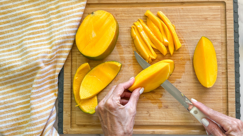 hand slicing off mango skin