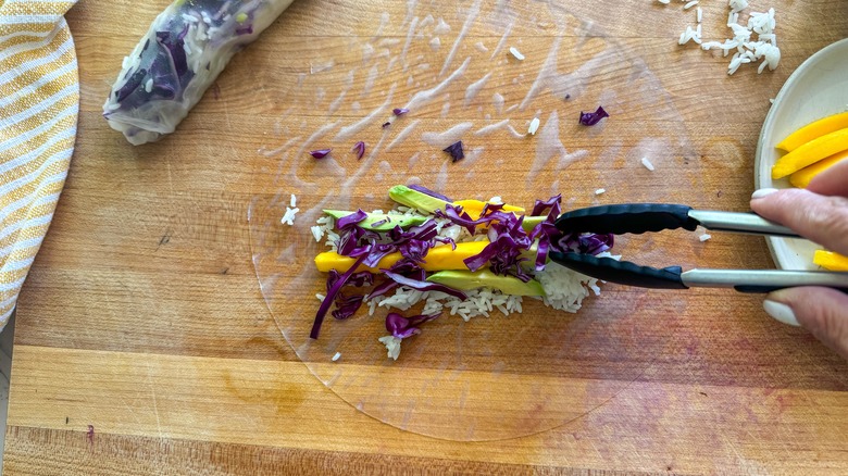 tongs adding ingredients to roll