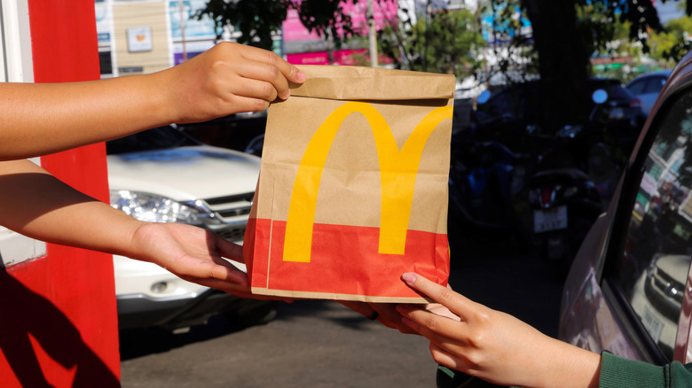 Closeup hands passing McDonald's branded bag into car