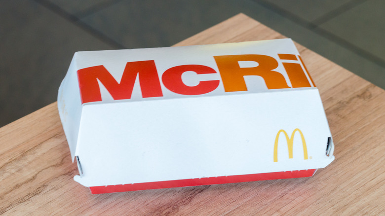 A clamshell box reading "McRib" sits closed on a wood-patterned table.