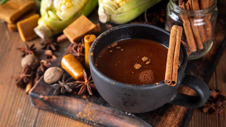 A mug of Mexican hot chocolate surrounded by spices