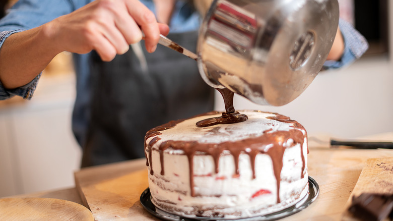 woman pouring frosting on cake