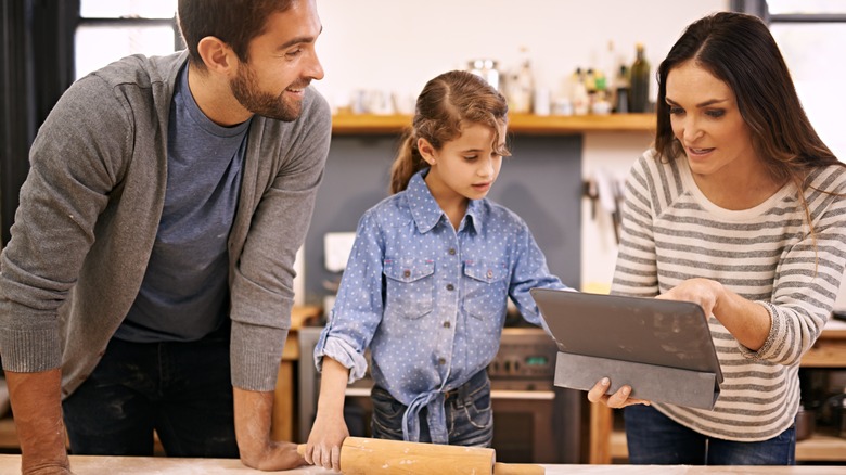 A family reading a recipe while baking in the kitchen