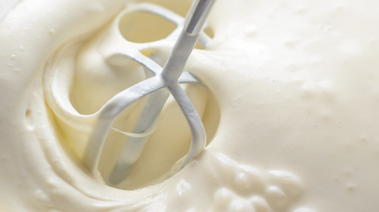 A close up of a beater mixing icing