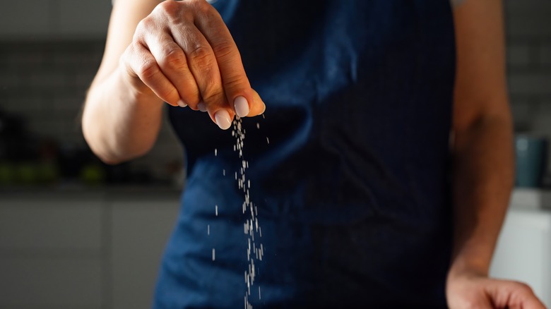 Person adding salt to a pan