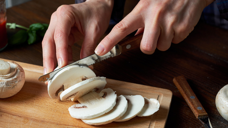 Person slicing mushrooms on a cutting board