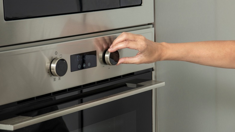 person adjusting oven temperature