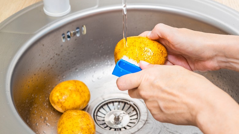 scrubbing potatoes in sink