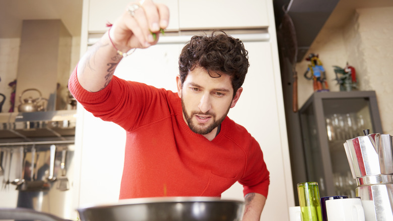 A chef adding seasonings to a pan