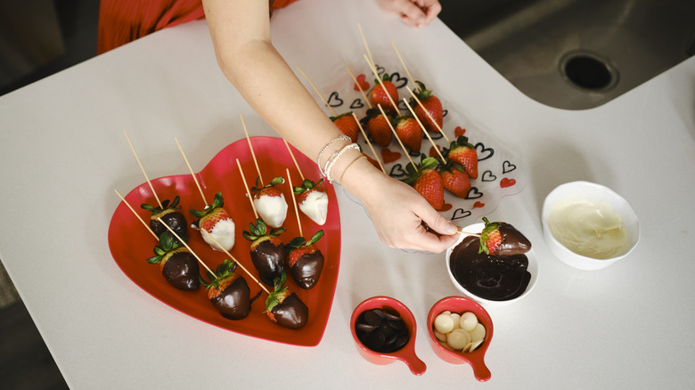 A person dipping a strawberry in melted chocolate