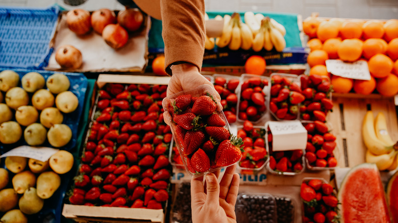 A person buying strawberries from a market