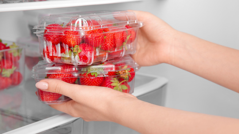 A person taking strawberries out of the fridge