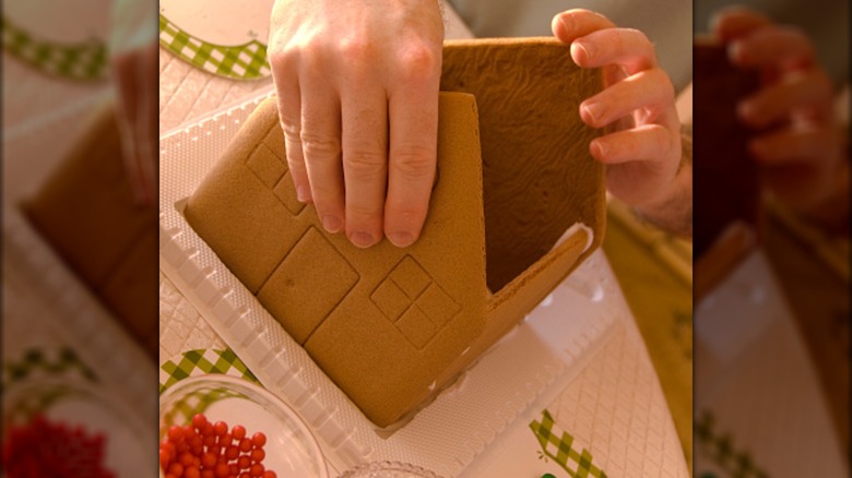 A person putting together a gingerbread house