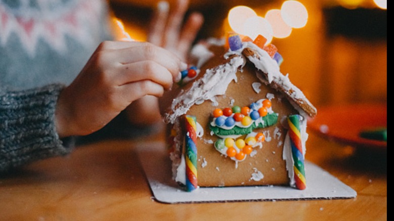 A person decorating a gingerbread house