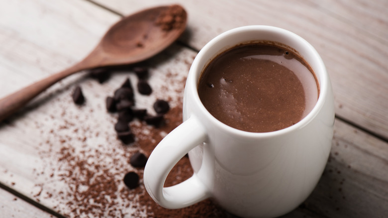 A wooden spoon next to a mug with hot chocolate