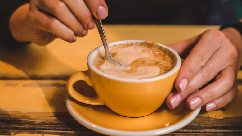 A person stirring a mug of hot chocolate