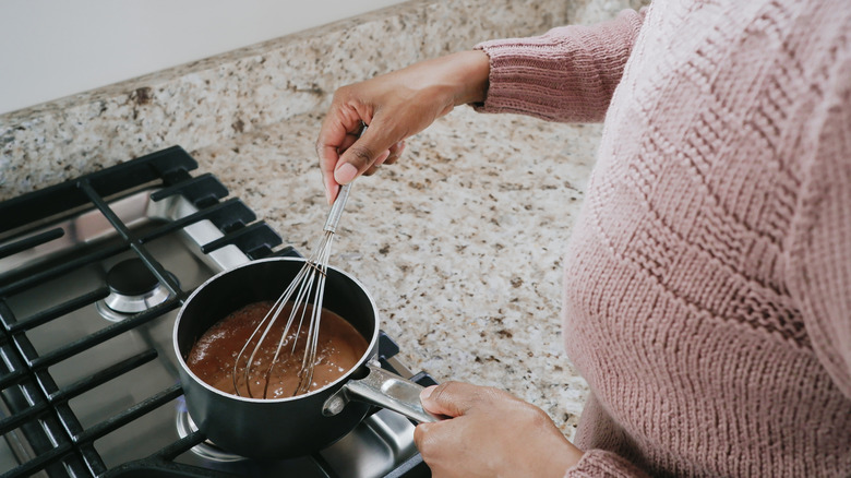 A person whisking hot chocolate over the stove