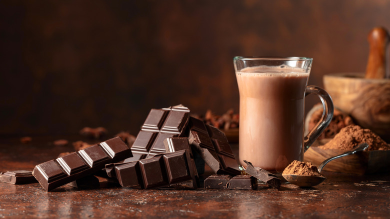 A solid chocolate bar next to a mug of hot chocolate