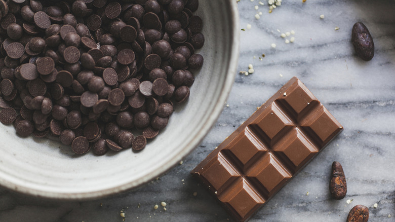 A bowl of chocolate chips and a chocolate bar