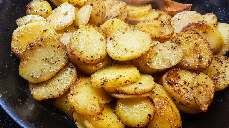 Close-up of a pan of potato slices being shallow fried