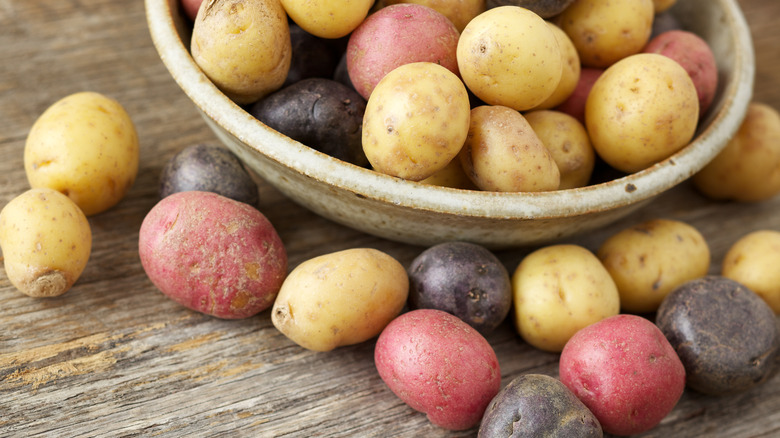 bowl of several different colored potatoes on a wooden surface