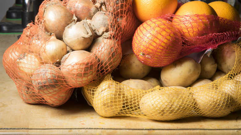 nets of onions, potatoes and oranges on a table