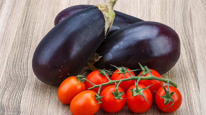 Eggplants and tomatoes on a wooden surface