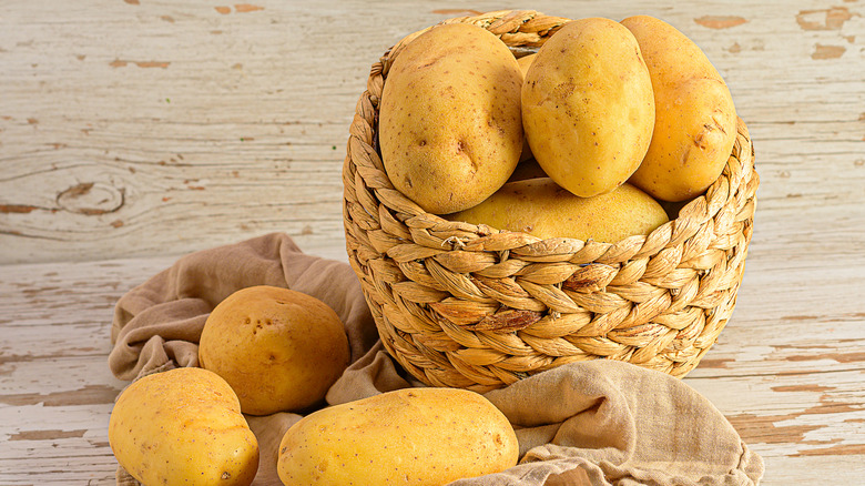 a wicker basket filled with potatoes on a wooden table