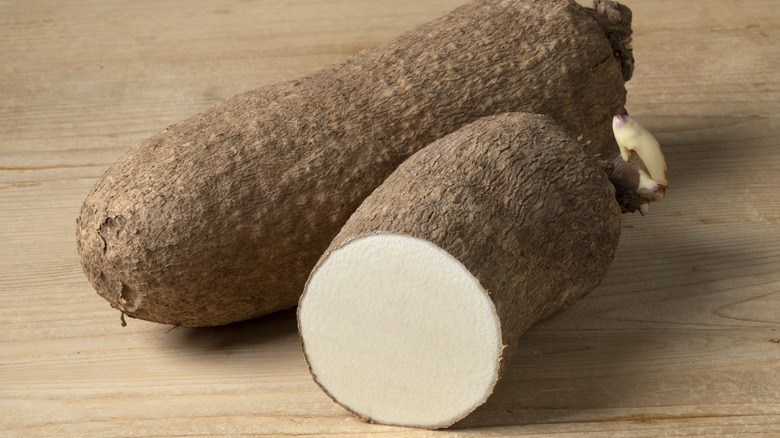 Large whole and halved yam with brown skin and white insides.