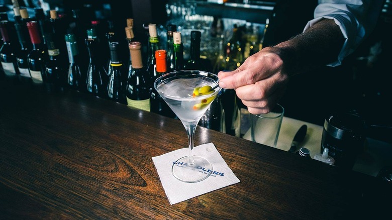 Bartender placing olives in martini