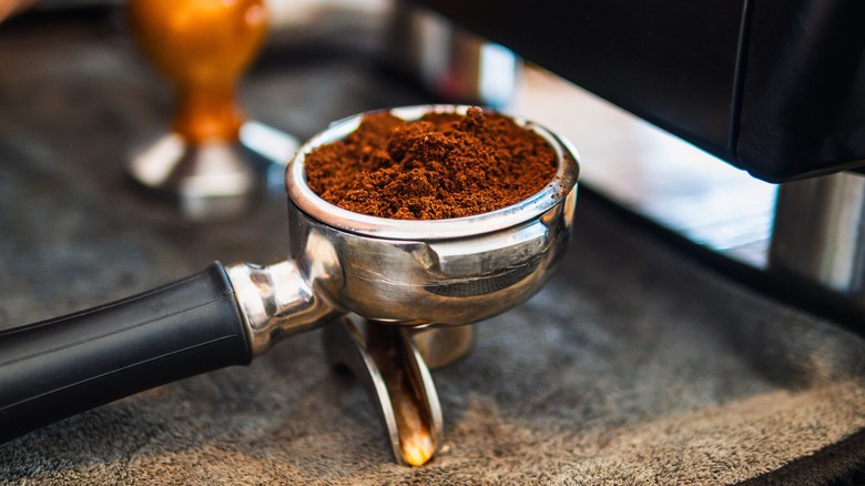 Espresso grounds in a portafilter on counter.