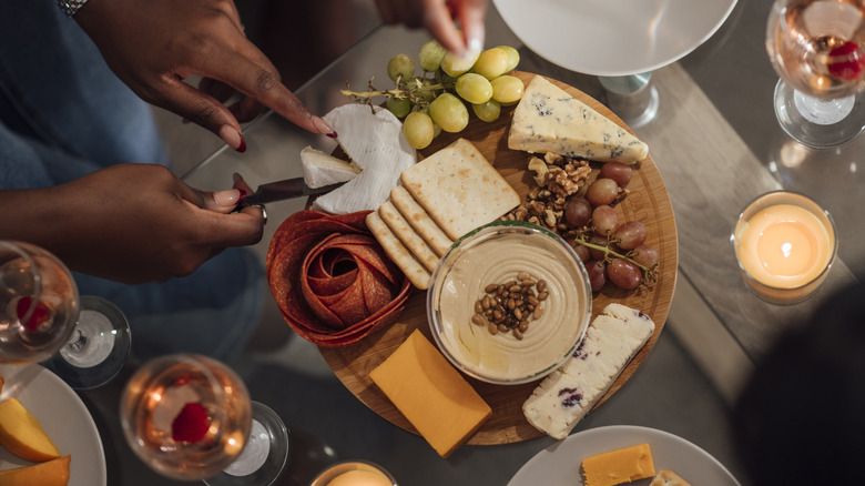 People eating from charcuterie board