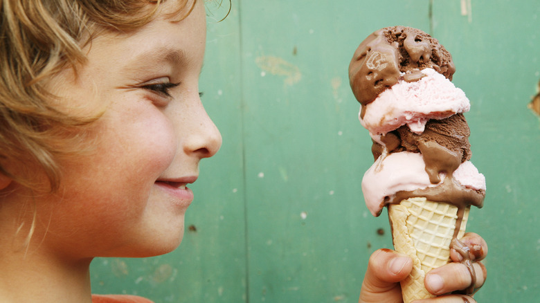 Young girl looks at ice cream melting in a waffle cone