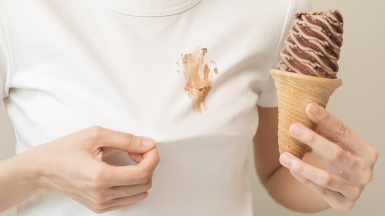 Chocolate stain on white shirt with hand holding ice-cream cone