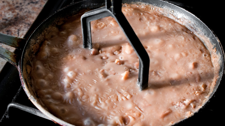 Refried beans being mashed in pan