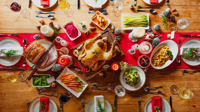 Festive dinner table with roasted chicken, vegetables, and drinks.