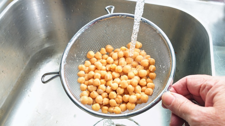 Beans in strainer being rinsed over sink