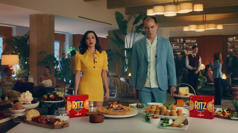 Aubrey Plaza and Michael Shannon standing before table of Ritz crackers