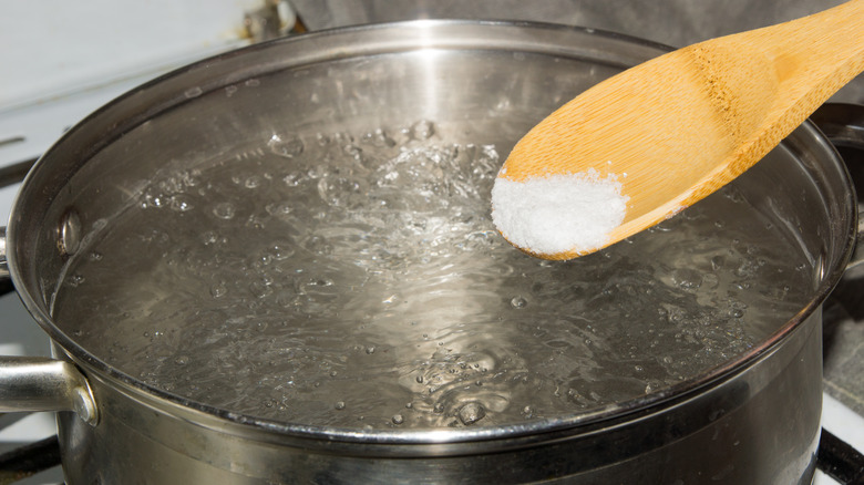 Wooden spoon with salt over boiling water. 