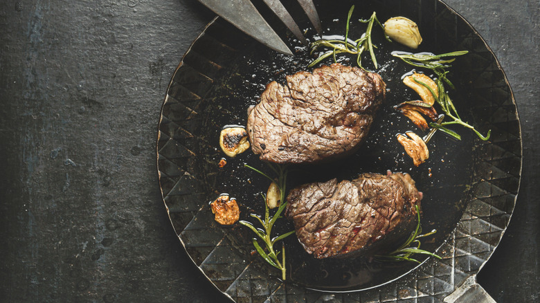 two filet mignon steaks on a plate with herbs