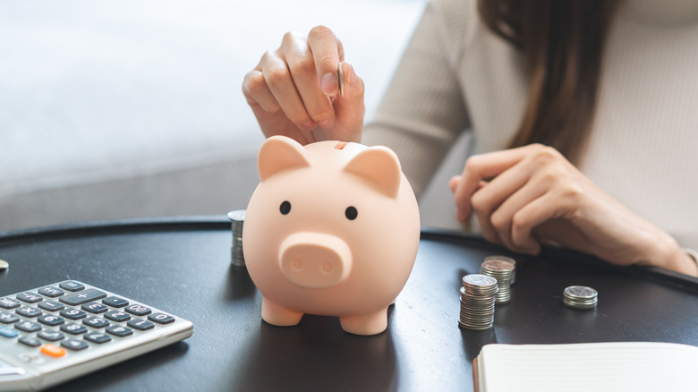 woman putting coins in a piggy bank