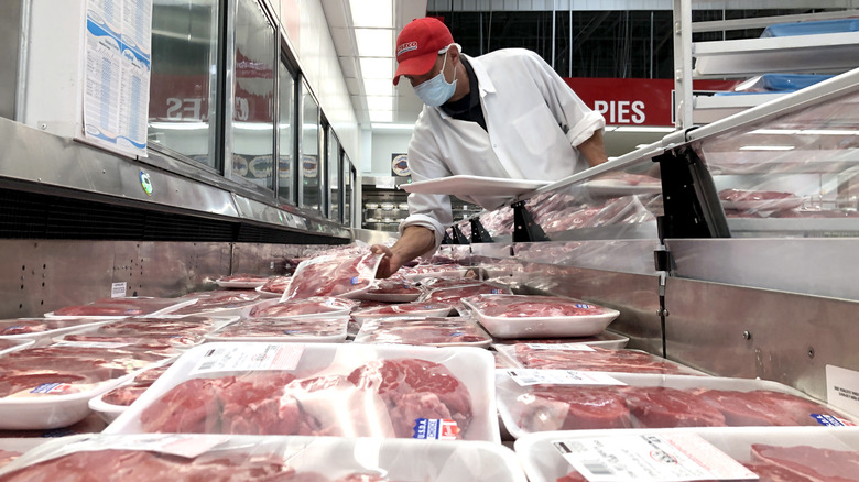 Costco employee with steaks in meat section at costco