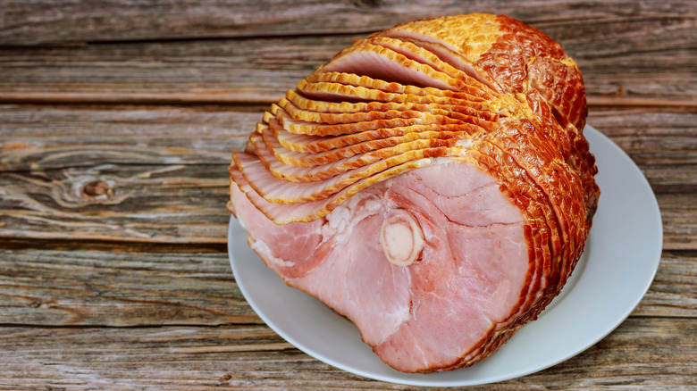 A spiral-cut ham rests on a tabletop platter