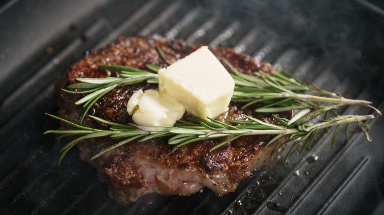 Cooked steak in a pan with butter and herbs