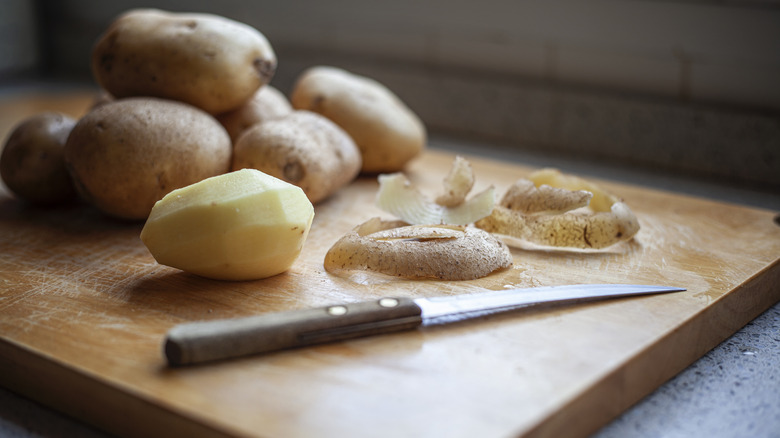 Peeled potato next to a knife